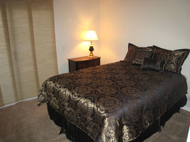 Lower unit primary bedroom alternate view with lamp and bamboo blinds