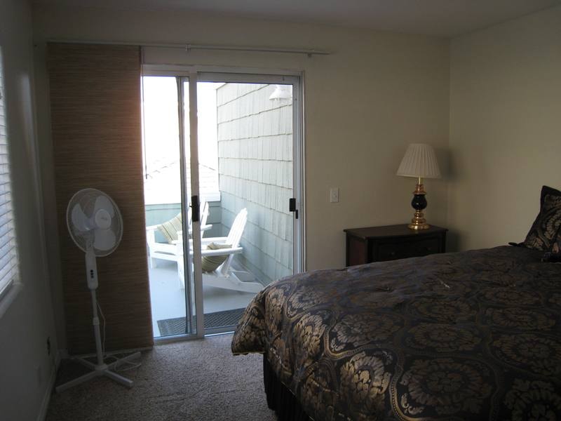Lower unit bedroom with sliding glass door opening to private patio with Adirondack chairs