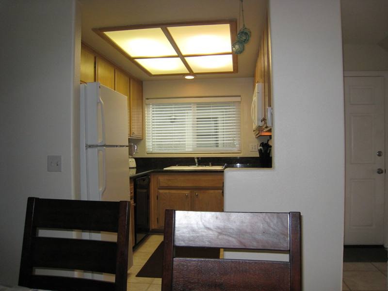 Lower unit kitchen with wood cabinetry, black countertops, and white refrigerator