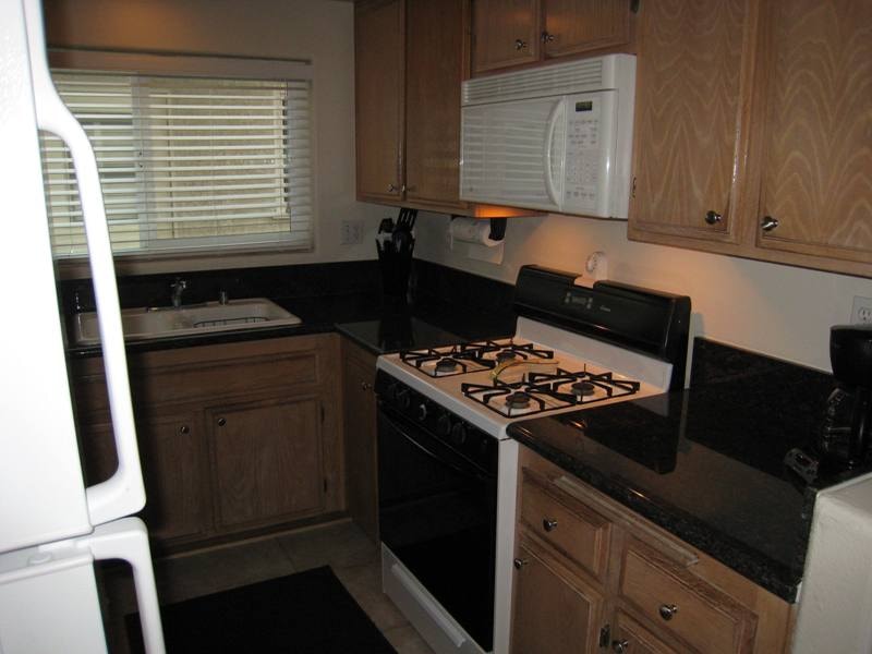 Lower unit kitchen viewed from dining area with wood cabinetry and white appliances