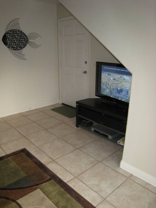 Lower unit entry area with TV under staircase and tile floors