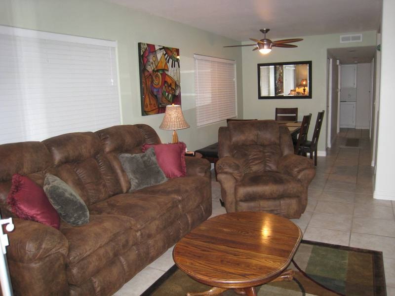 Lower unit living room with brown leather sofas, ceiling fan, and colorful wall art
