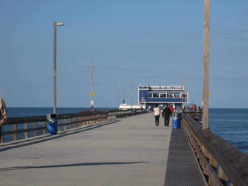 Newport Beach sand with Dory Fleet area, palm trees, and beachfront shops