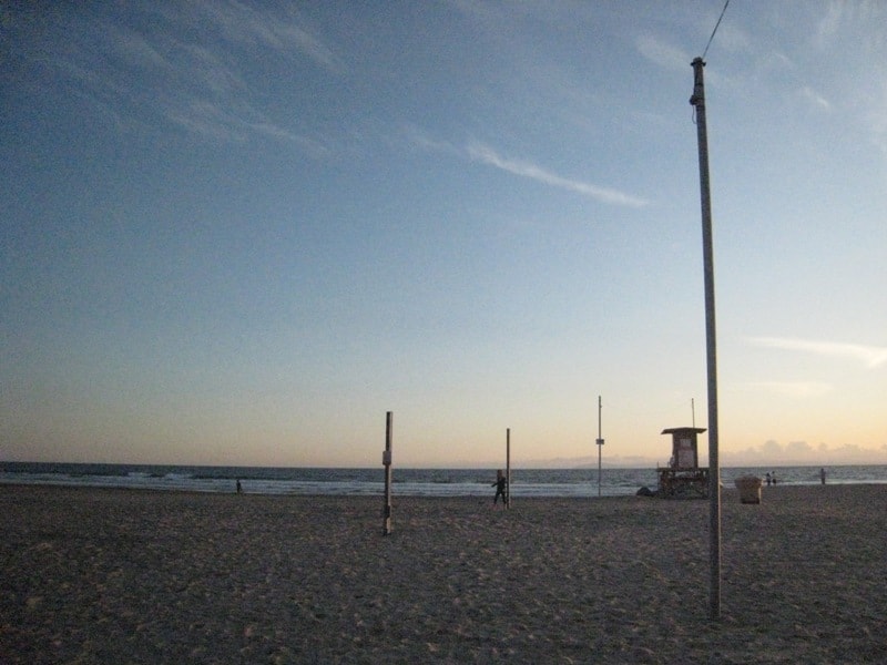 Beach volleyball court at sunset with lifeguard tower in the background