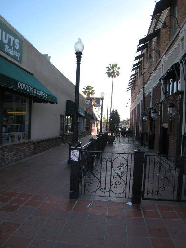 Charming alley near Seaside Donuts Bakery with iron gate and palm trees