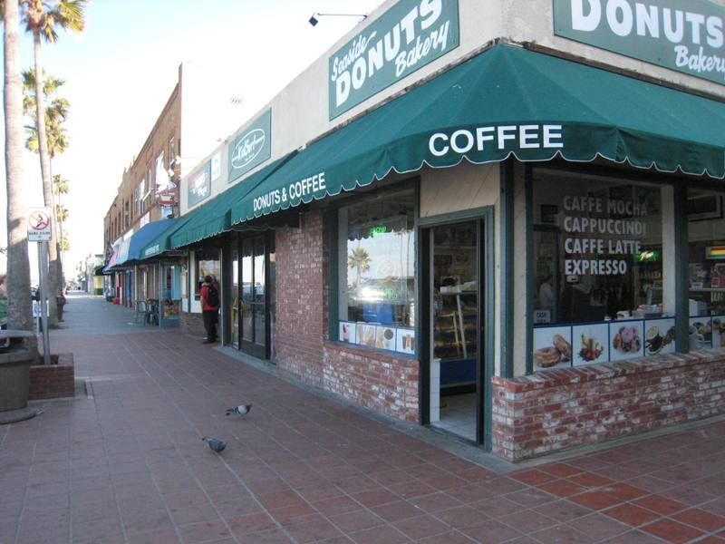 Seaside Donuts Bakery storefront with coffee and donut signs on Newport Beach boardwalk