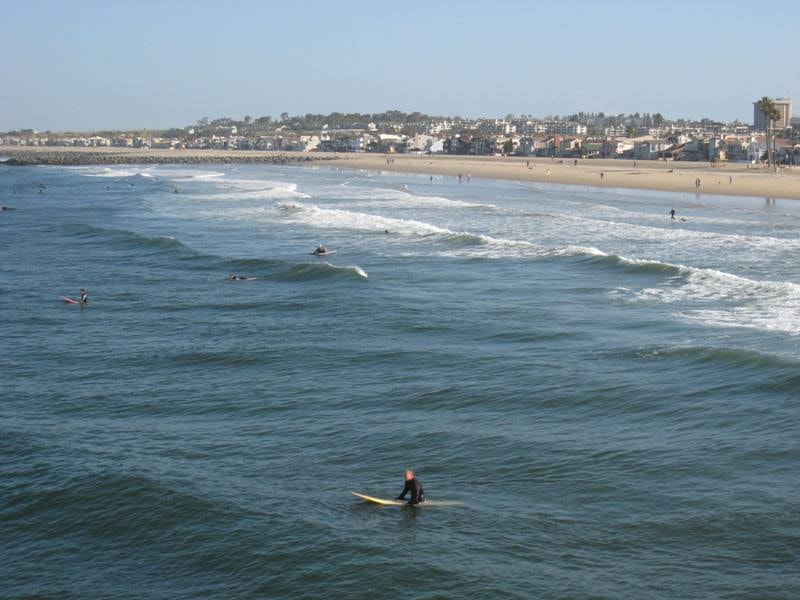 Surfers in the waves at Newport Beach with coastal homes in the background