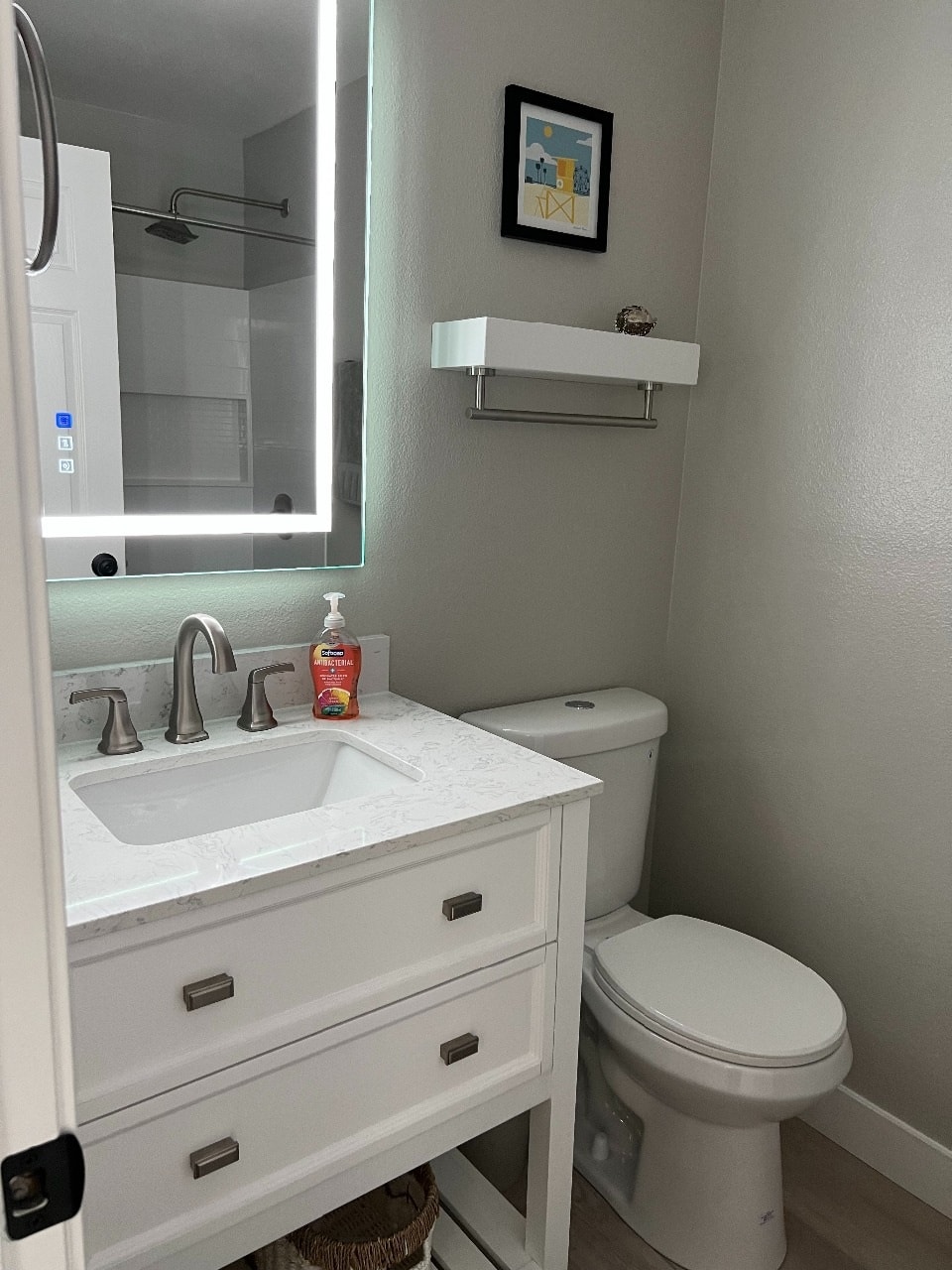 Upper unit bathroom with lighted vanity mirror and marble countertop
